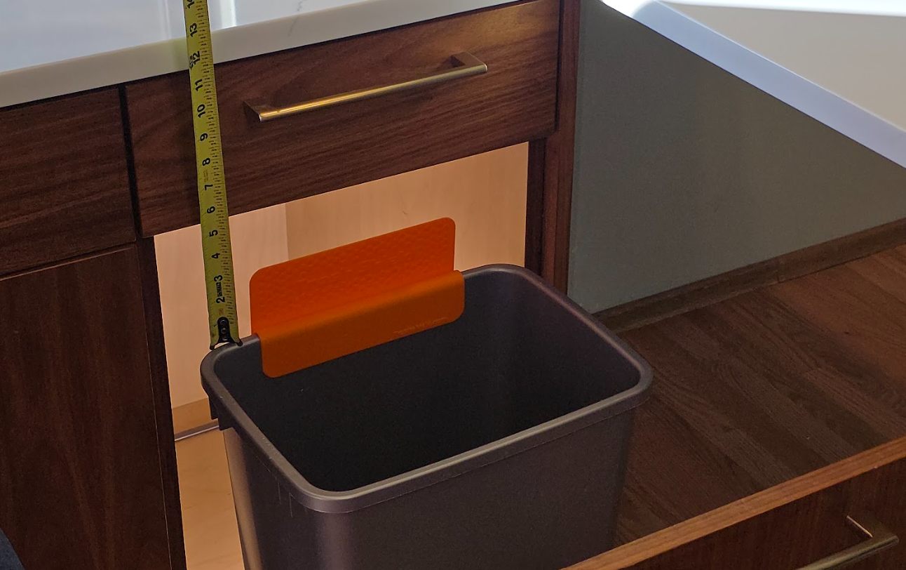 Diagram showing where to measure the gap, from the top of the bin's rim to the underside of the cabinet above, with a Trash Shield overlay